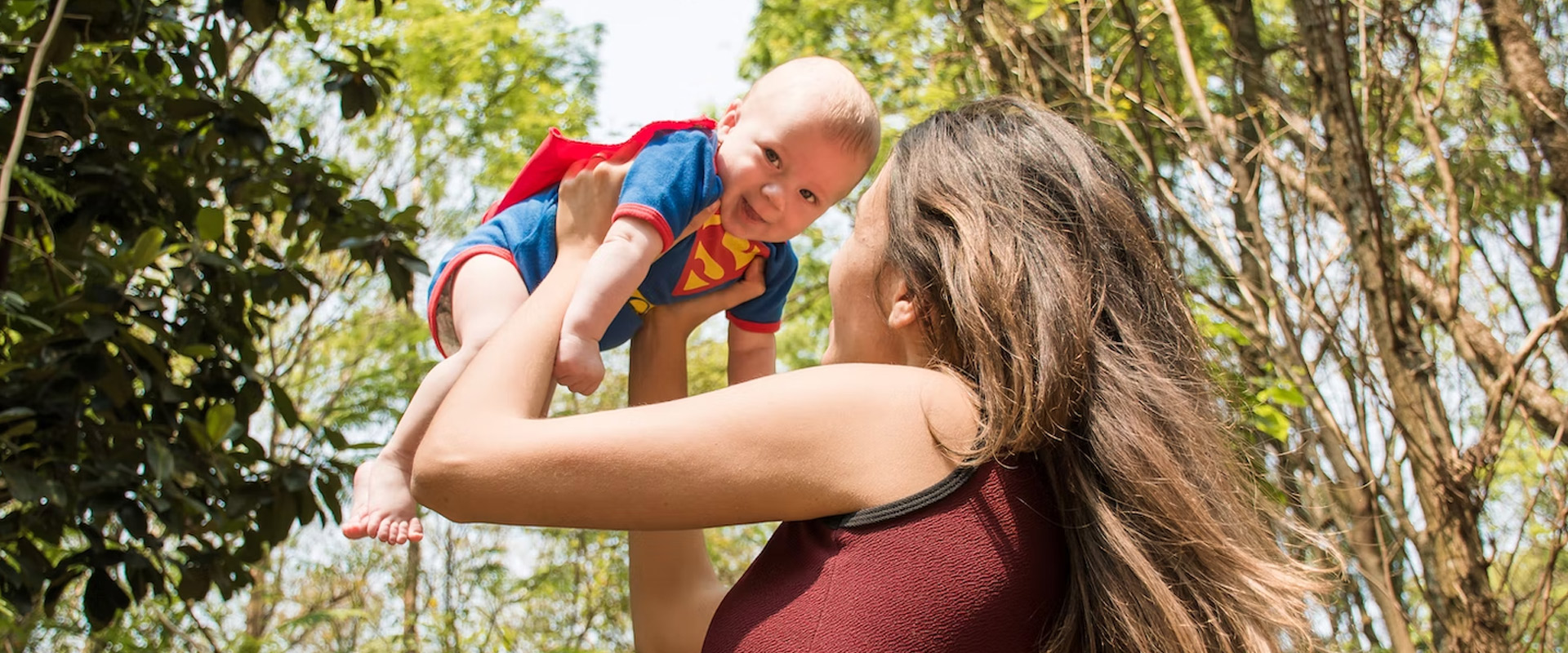 Mom holding baby in superman costume
